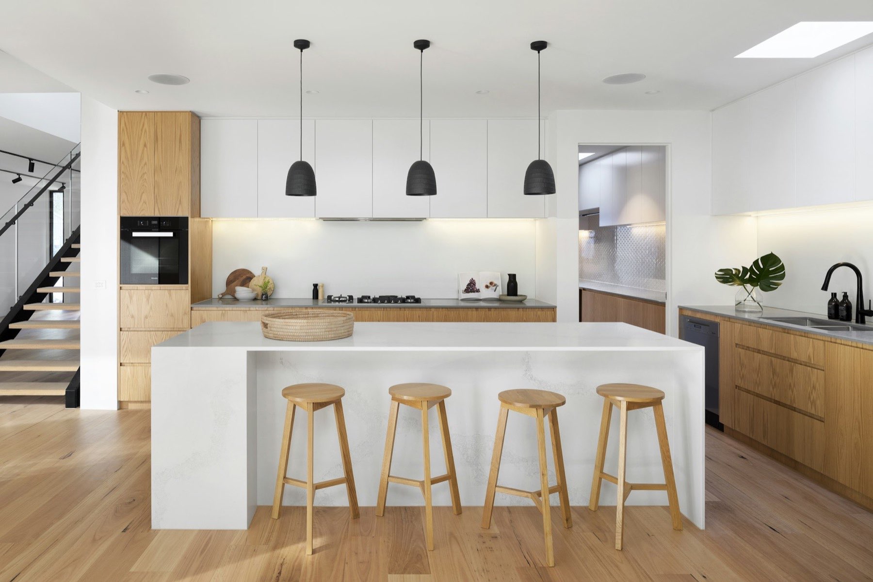 Pale kitchen with an oak island, stool run and pendant lighting