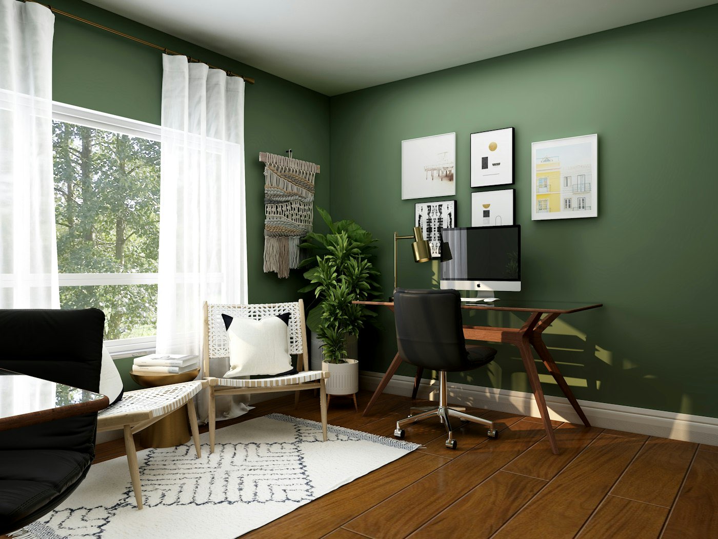 Home office with a deep green wall, framed prints and a work desk