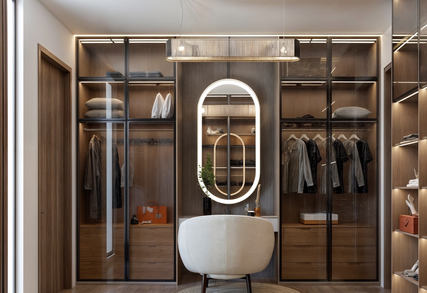 Walk-in wardrobe in smoked glass and bronze, lit mirror and a lounge chair